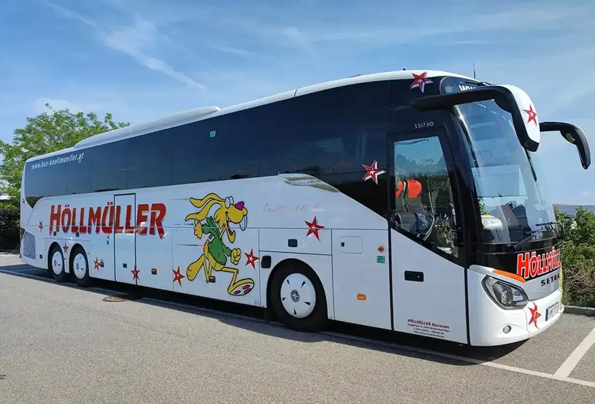 Langer Höllmüller-Reisebus mit drei Achsen seitlich auf einem Parkplatz