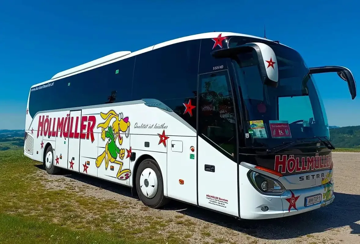 Höllmüller-Reisebus seitlich unter blauem Himmel vor einer Hügellandschaft